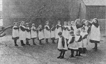 Two older girls form the archway for this game of 'oranges and lemons'. This game, which originated in the 17th century, was played by singing the popular nursery rhyme while children danced in line through the archway. It ended when the children forming the archway let their arms fall down around one 'captured' child. 