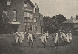 Girls playing Ring-a-ring-a-roses in the back garden of the Loughton home. Playgrounds used to be full of the sounds of singing games like this. The song 'Ring-a-ring-a-roses' was actually based on the unpleasant events of the Black Death in London during 1665 - when people would wear posies of flowers to hide the stench of the plague. 